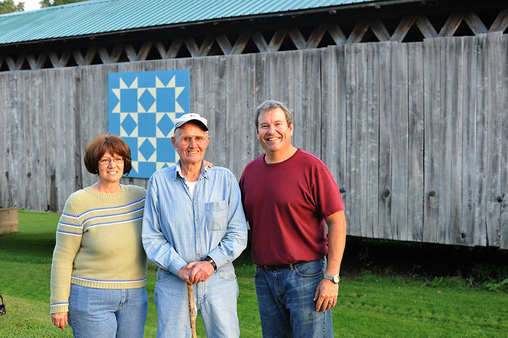 Standing with the new barn quilt at the Graham Road covered bridge are (from left) Kathy McCarty, Bob Benson and Jeff Scribben.