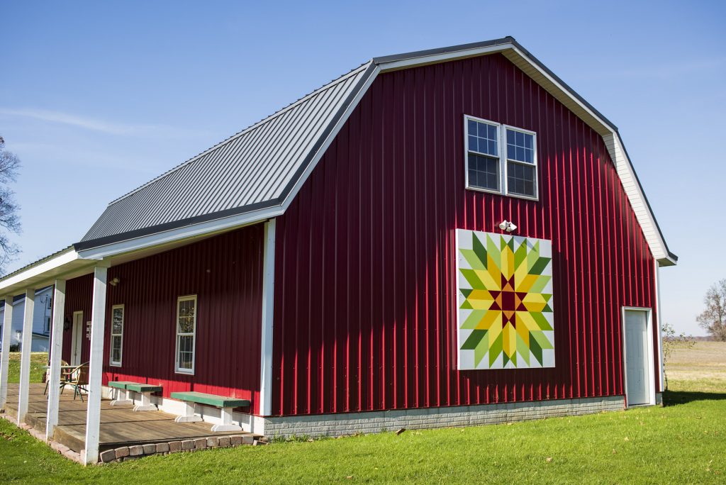 Barn quilt on side of red barn.